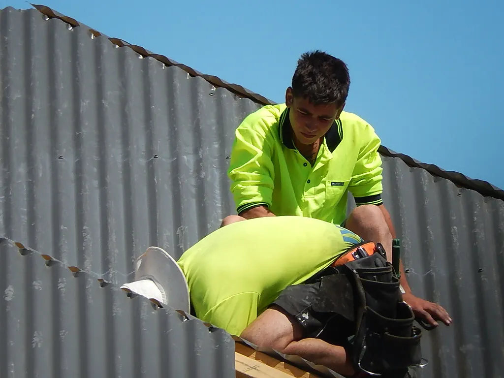 Roofers in protective gear working on a roof
